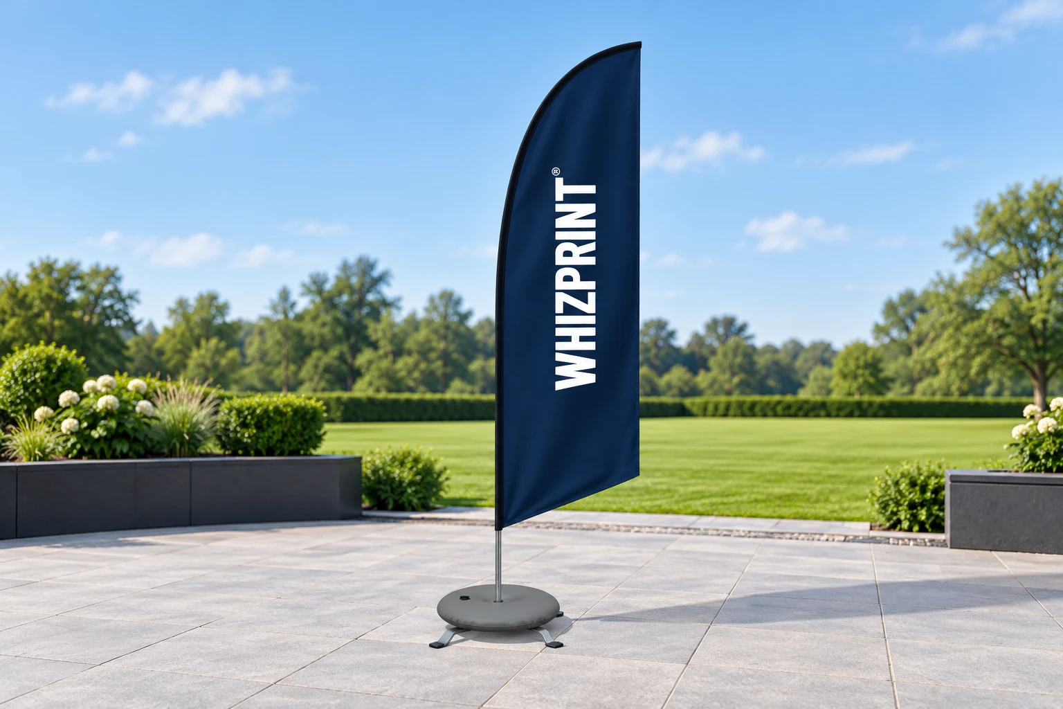 Illustrative Whizprint feather flag on paving with a cross base and circular weight; a lawn is visible beyond.