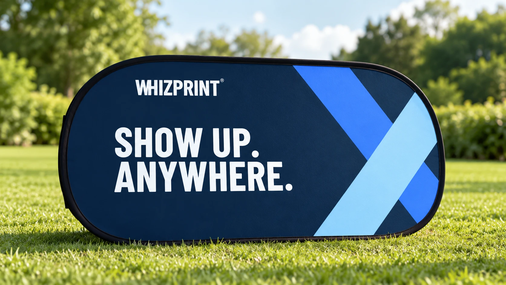 Illustrative navy and blue Whizprint oval pop-up banner on a grass lawn.